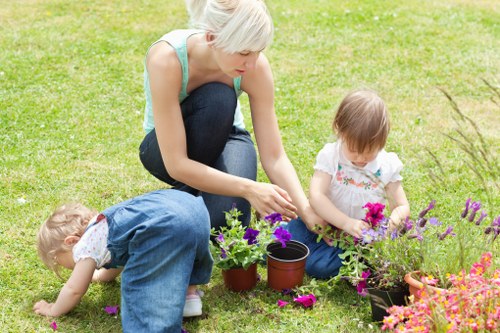 Gardener wearing PPE including helmet, boots and gloves operating machinery
