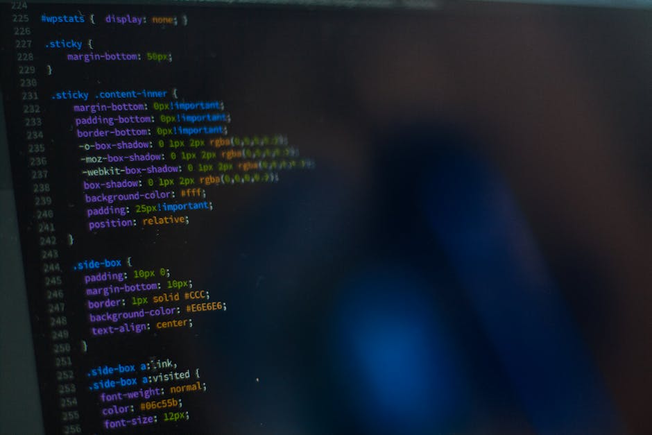 A close-up photograph of a computer screen displaying lines of colorful programming code. The code includes various CSS styling elements, such as properties for margins, borders, shadows, background c